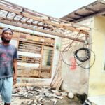 Dani usai membersihkan puing bekas rerumputan atap rumahnya yang ambruk.(foto: dare)