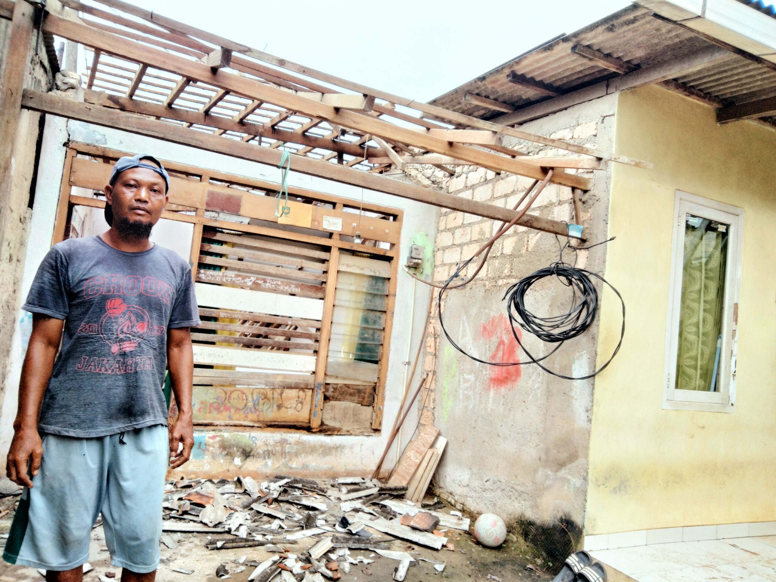 Dani usai membersihkan puing bekas rerumputan atap rumahnya yang ambruk.(foto: dare)